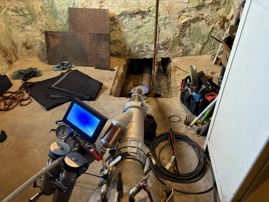 TID Trenchless technician deploying sewer camera inspection equipment at a residential pipe access point in Southeastern Massachusetts