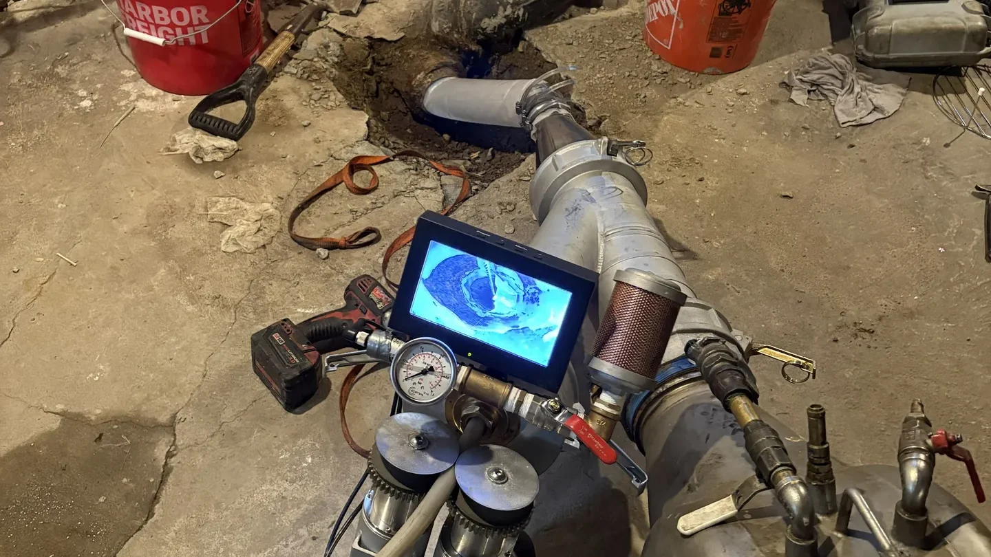 Pipe lining equipment and camera monitor in use during a residential sewer line repair in a Massachusetts basement