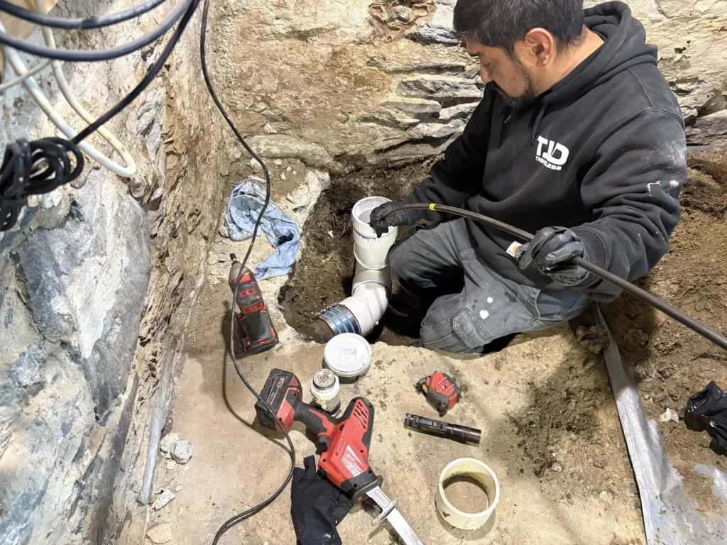 TID Trenchless technician performing sewer pipe repair at an excavated access point in Massachusetts
