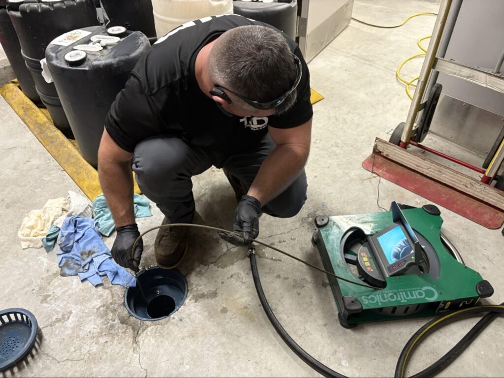 A TID Trenchless technician runs a sewer camera into a floor cleanout during a Plymouth, MA drain inspection.