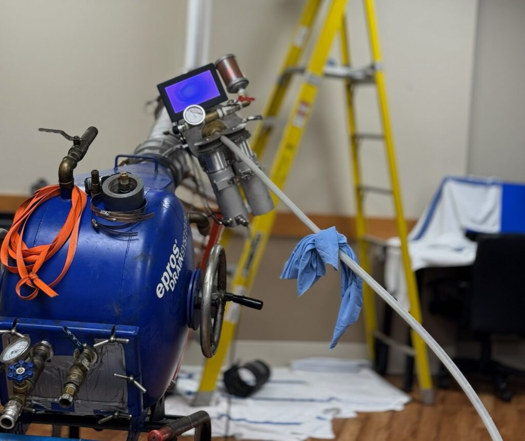 Pipe lining equipment and camera monitor set up for trenchless sewer repair inside a building