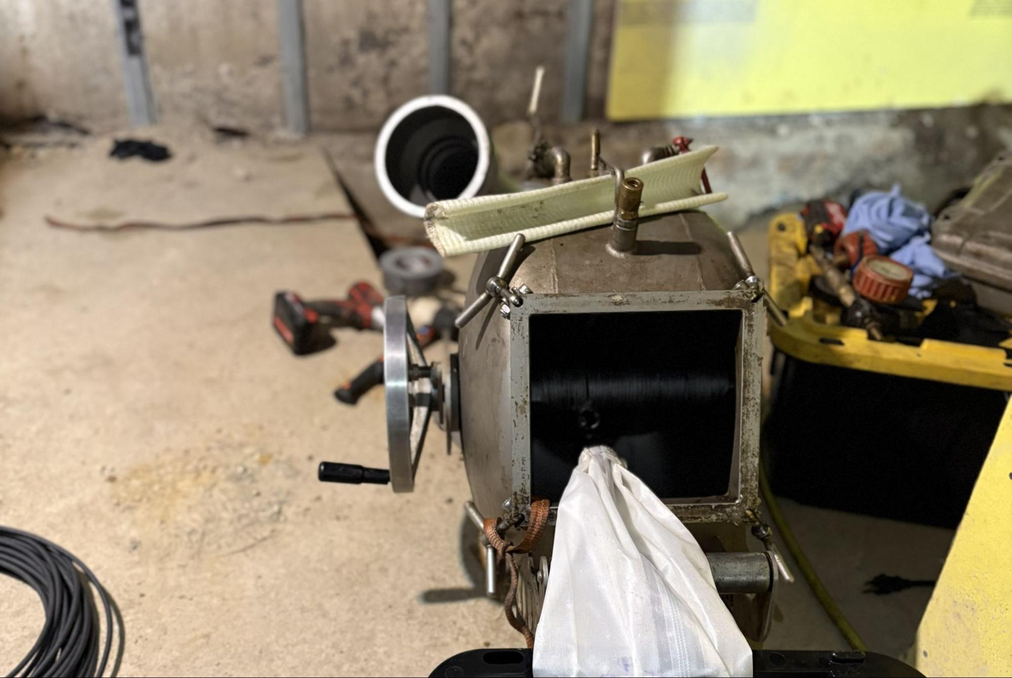 Technician feeding a sewer camera into a basement drain before epoxy pipe coating